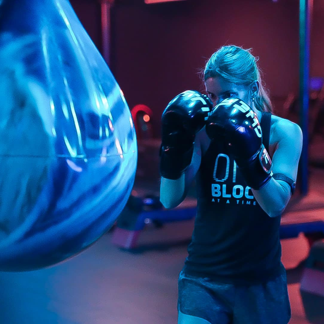 An image of a woman in fighter stance wearing boxing gloves at the heavy bag at Chamfit Studios in Evansville, IN