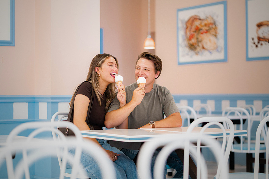 A man and woman sit in a local ice cream shop in Evansville, Indiana eating ice cream cones on a low-key date