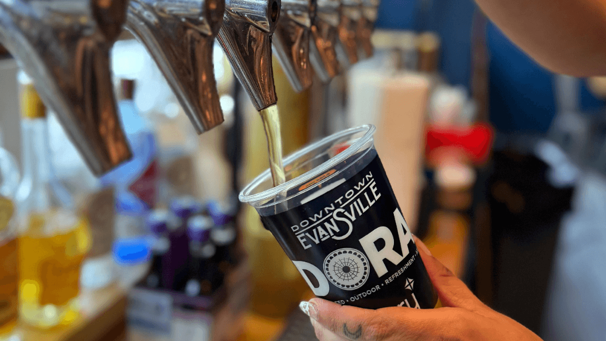 A bartender pouring a glass of beer into an approved DORA reusable cup
